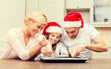 Image showing happy family in santa helper hats making cookies