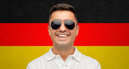 Image showing face of smiling man in sunglasses over german flag