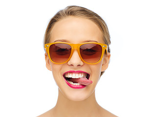 Image showing happy young woman in sunglasses showing tongue