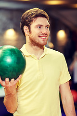 Image showing happy young man holding ball in bowling club