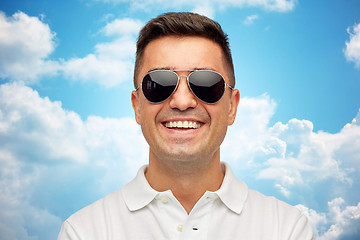 Image showing face of smiling man in sunglasses over blue sky