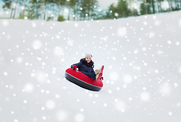 Image showing happy teenage girl sliding down on snow tube