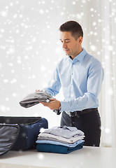 Image showing businessman packing clothes into travel bag