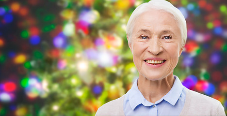 Image showing happy senior woman face over christmas lights