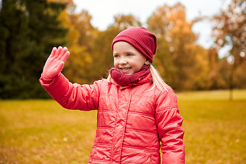 Image showing happy little girl waving hand in autumn park