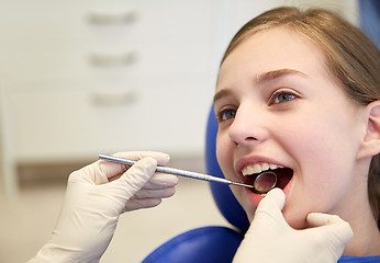 Image showing hands with dental mirror checking girl teeth