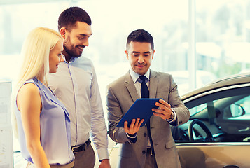 Image showing happy couple with car dealer in auto show or salon