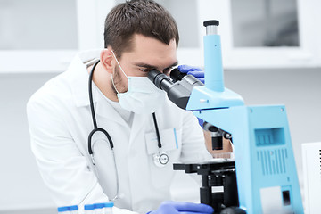 Image showing young scientist looking to microscope in lab