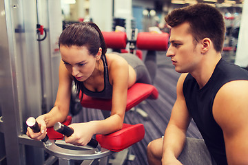 Image showing young woman with trainer exercising on gym machine