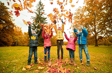 Image showing happy children playing with autumn leaves in park