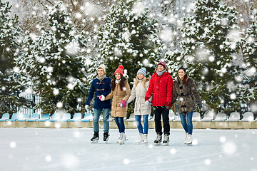 Image showing happy friends ice skating on rink outdoors