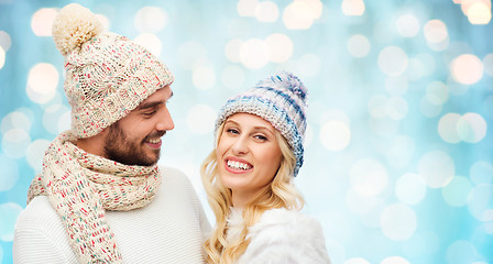 Image showing smiling couple in winter clothes over blue lights