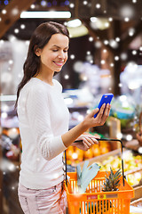 Image showing happy woman with basket and smartphone in market