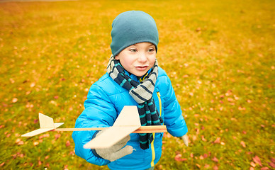 Image showing happy little boy playing with toy plane outdoors
