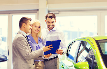 Image showing happy couple with car dealer in auto show or salon