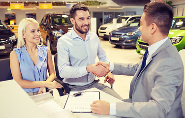 Image showing happy couple with car dealer in auto show or salon