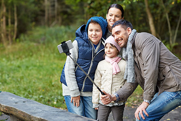 Image showing happy family with smartphone selfie stick at camp