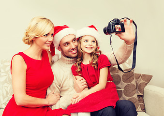 Image showing smiling family in santa helper hats taking picture