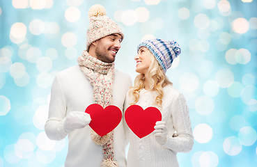 Image showing smiling couple in winter clothes with red hearts