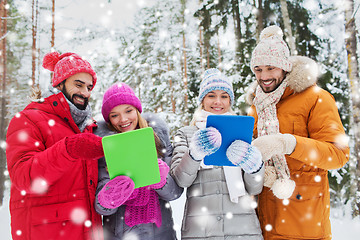 Image showing smiling friends with tablet pc in winter forest