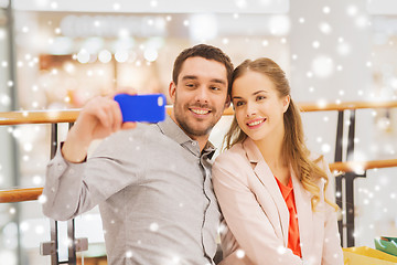 Image showing happy couple with smartphone taking selfie in mall