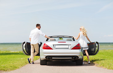 Image showing happy man and woman near cabriolet car at sea