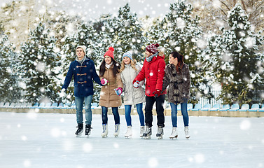 Image showing happy friends ice skating on rink outdoors