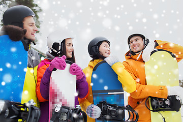 Image showing happy friends in helmets with snowboards talking