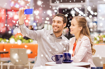 Image showing happy couple with smartphone taking selfie in mall