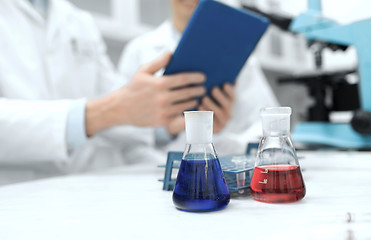 Image showing close up of scientists with flasks and tablet pc