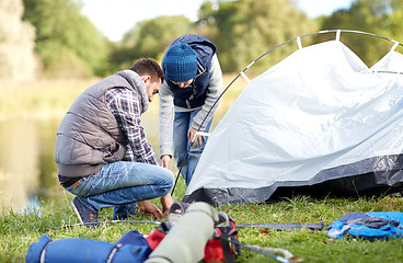 Image showing happy father and son setting up tent outdoors