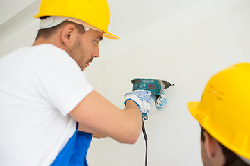 Image showing close up of builders with drill perforating wall