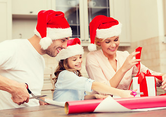 Image showing smiling family in santa helper hats with gift box