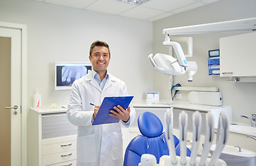 Image showing happy male dentist with clipboard at dental clinic