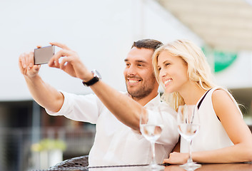 Image showing happy couple taking selfie with smartphone at cafe