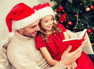 Image showing smiling father and daughter reading book