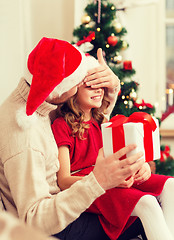 Image showing smiling father surprises daughter with gift box