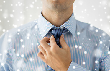 Image showing close up of man in shirt adjusting tie on neck