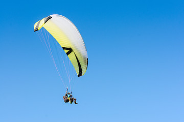 Image showing Paragliding sport flight on soaring wing in clear blue sky