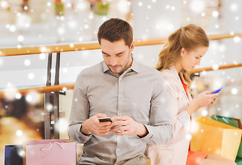 Image showing couple with smartphones and shopping bags in mall