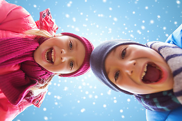 Image showing happy little boy and girl over blue sky with snow