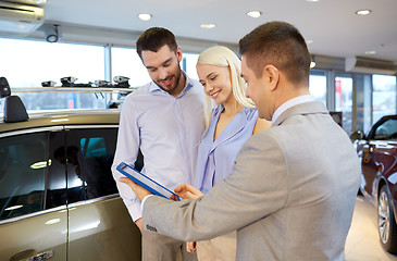 Image showing happy couple with car dealer in auto show or salon