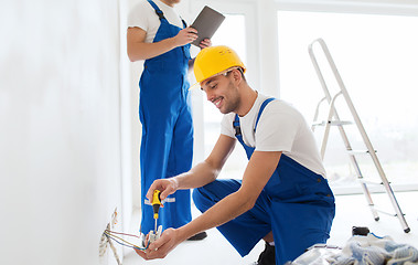 Image showing builders with tablet pc and fixing wiring indoors