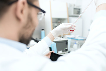 Image showing close up of scientist with tube and pipette in lab