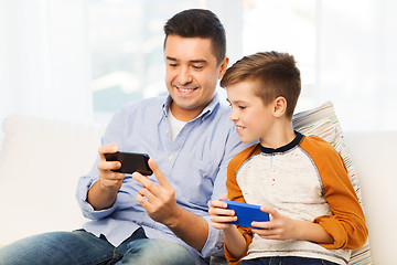 Image showing happy father and son with smartphones at home