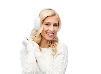 Image showing smiling young woman in winter earmuffs and sweater