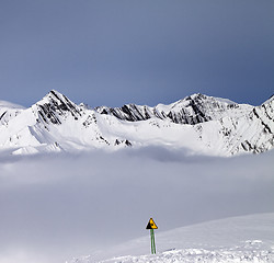 Image showing Mountains in mist and warning sing on off-piste slope