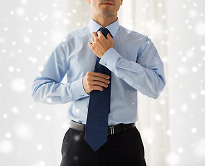 Image showing close up of man in shirt adjusting tie on neck