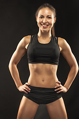 Image showing Muscular young woman athlete looking in camera on black 