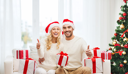 Image showing happy couple with christmas gifts and thumbs up